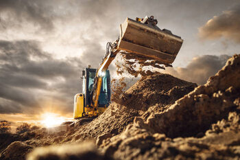 Canvas Print Excavator scooping dirt in front of a dramatic sky