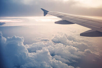 Poster Image of airplane wing flying above the clouds