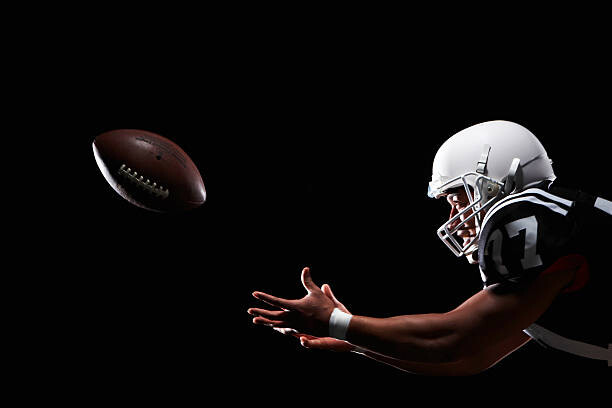 Camisola American football player catching ball, side view
