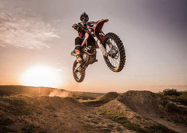 Valokuvataide Motocross rider performing high jump at sunset.