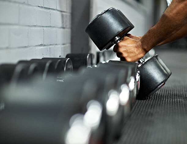 Camisola Athletic Male Picking Up Dumbbells in Gym