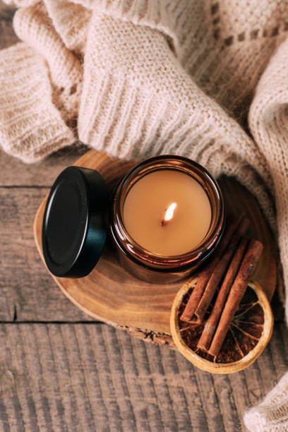 Canvas Print Candle in small amber glass jar with wooden wick on wooden stand on background. Top view