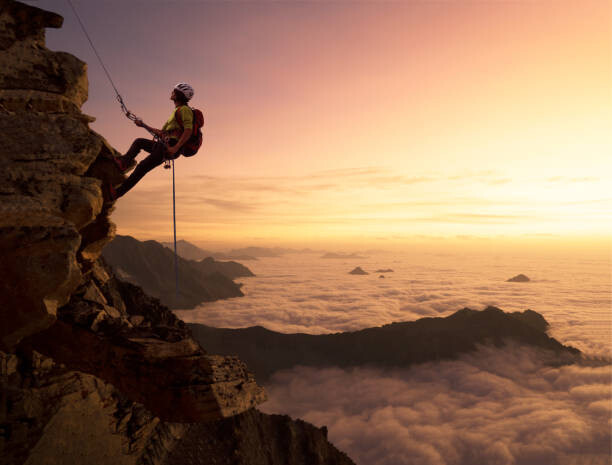 Canvas Print Climber on a rocky wall over clouds