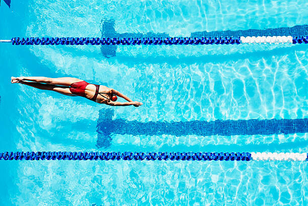 Canvas Print Female competitive swimmer diving into pool