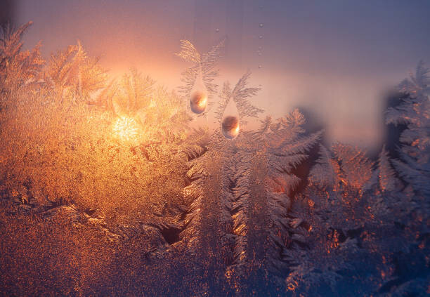 Canvas Print Frosty window with drops and ice pattern at sunset
