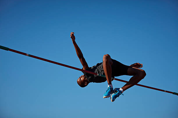 Canvas Print Male athlete doing high jump at sunset