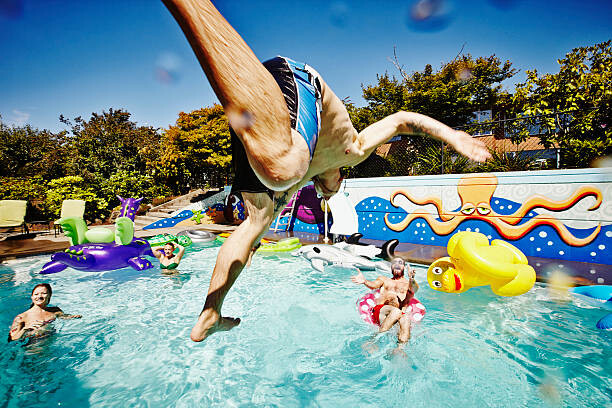 Canvas Print Man in mid air jumping into pool during party