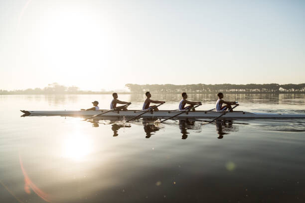 Canvas Print Mixed race rowing team training on a lake at dawn