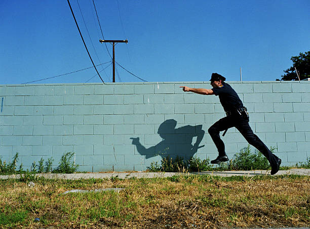 Canvas Print Policeman running next to cement wall,
