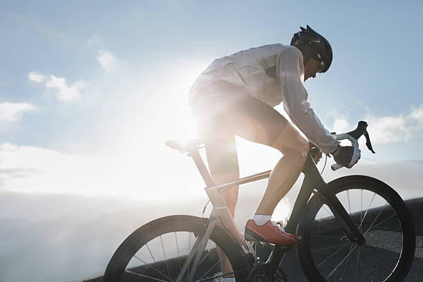 Canvas Print Silhouette of cyclist riding up in high mountains