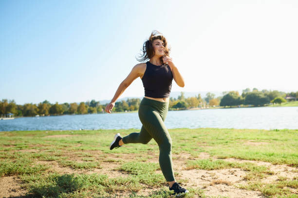 Canvas Print Smiling young woman jogging near lake on sunny day