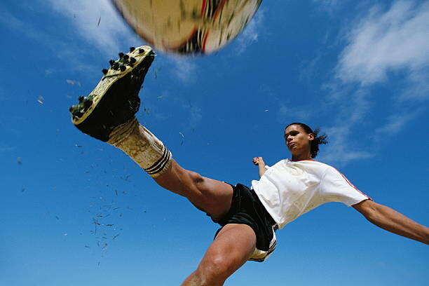 Canvas Print Soccer player kicking ball, low angle
