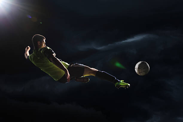 Canvas Print Soccer player kicking the ball in the air