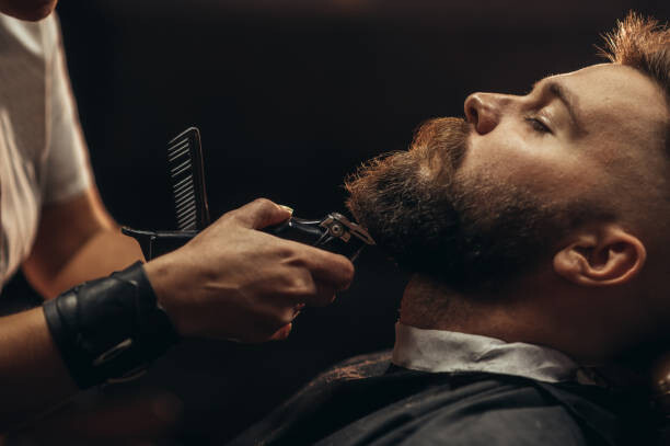Canvas Print Young bearded man getting beard haircut