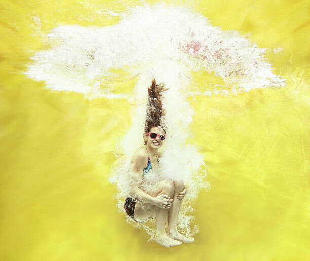 Canvas-taulu Girl jumping into water on yellow background