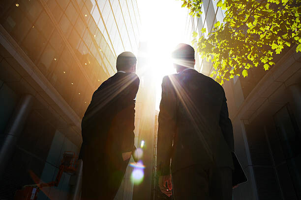 Juliste Two businessmen looking up into the sun.