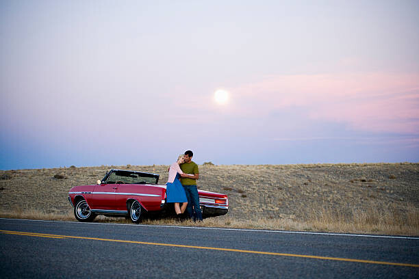 Bilde på lerret man and woman next to a red convertible
