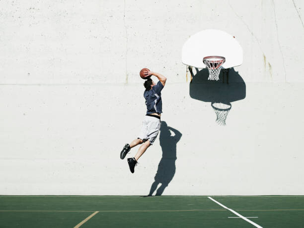 Camisola Man dunking basketball on outdoor court,