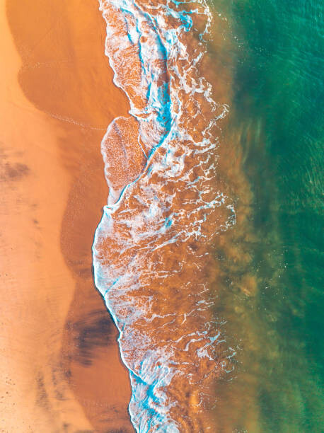 Autocolante Ocean waves breaking on white sand