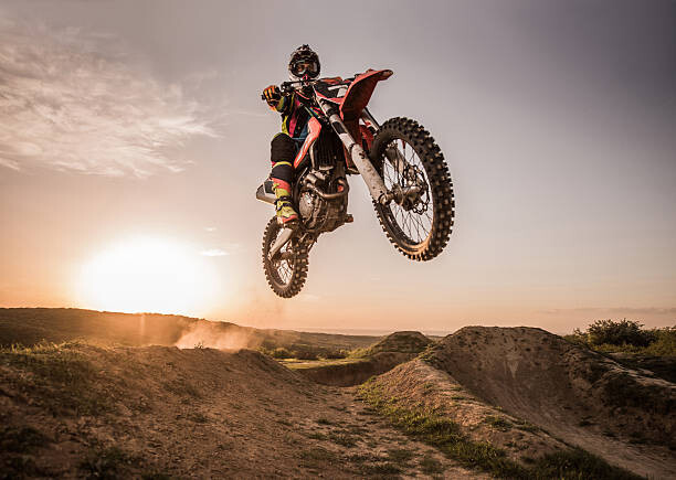 Plakat Motocross rider performing high jump at sunset.