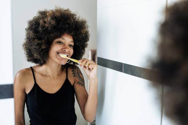 Plakat Multiracial woman brushing teeth in bathroom