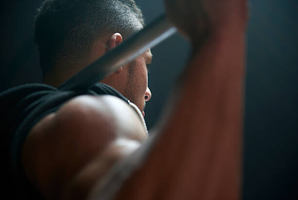 Poster Male athlete lifting weight bar black background