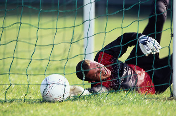 Poster Male football goalie lying on field,