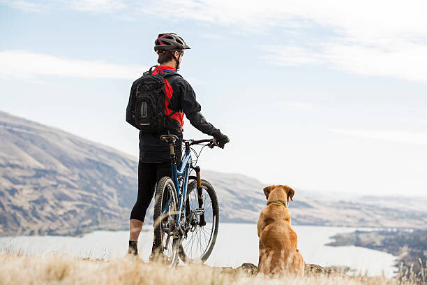 Poster A man mountian biking with his dog.