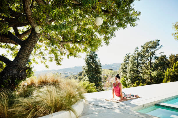 Poster Woman performing yoga on pool deck of home