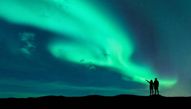 Poster Aurora borealis and silhouette of man and woman