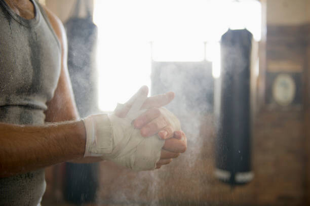Poster Caucasian boxer chalking hands in gymnasium