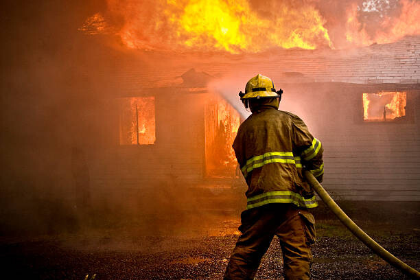 Poster Firefighter spraying water at a house fire