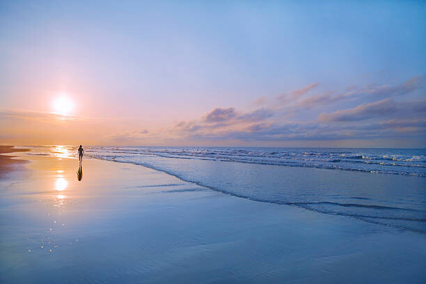 Poster Person walking on beach at sunrise