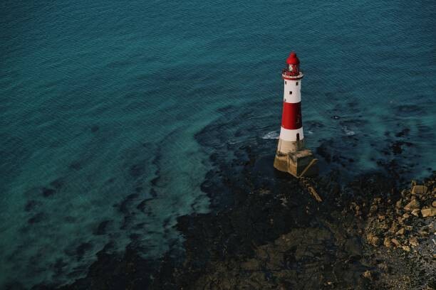 Poster Red and white lighthouse on the sea shore.