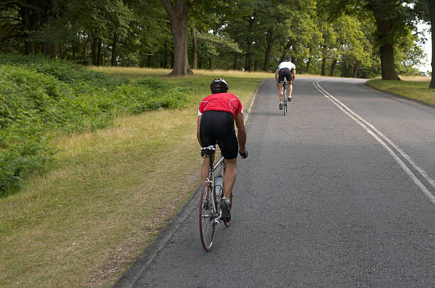Poster Two male cyclists on road, rear view