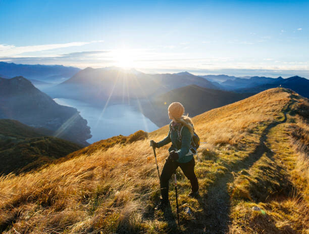Poster Woman hikes along ridgecrest above lake, valley