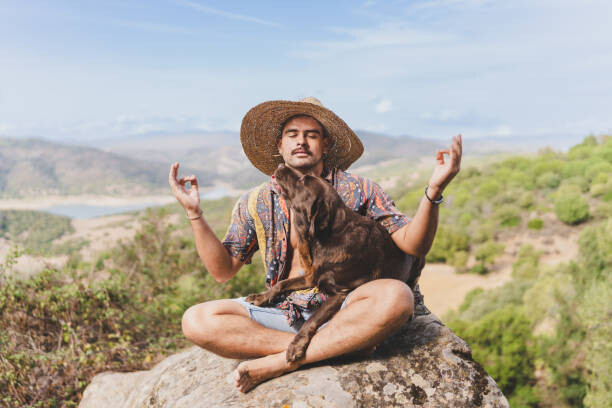 Плакат young man meditating in nature with his dog.