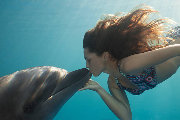 Poster Young Woman Kisses Dolphin Underwater, Sunbeams