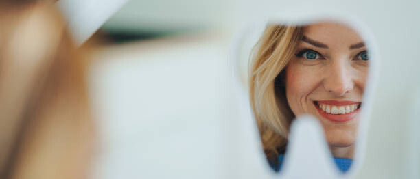 Αφίσα Happy patient looking at her teeth in mirror.