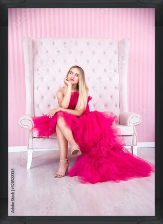 фотографія blonde smiling happy woman in pink dress sitting on pink chair in pink room  in